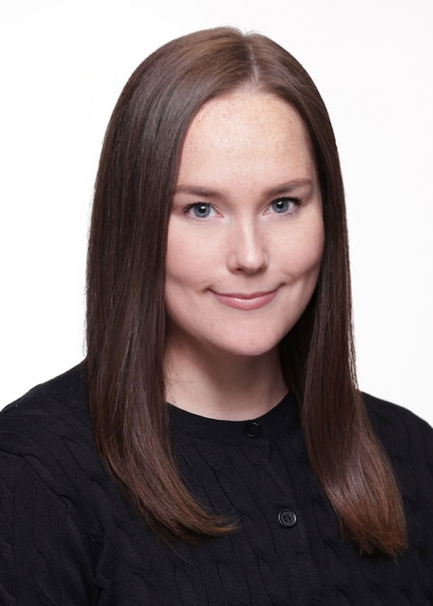 Sarah Kennedy, a woman with straight brown hair, fair skin, and blue eyes, is wearing a black sweater. She is facing forward and smiling slightly against a plain white background.